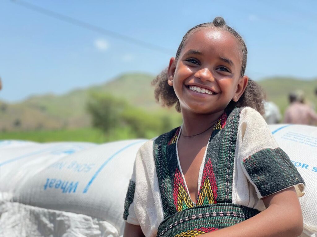 young girl in green and gray shirt smiling